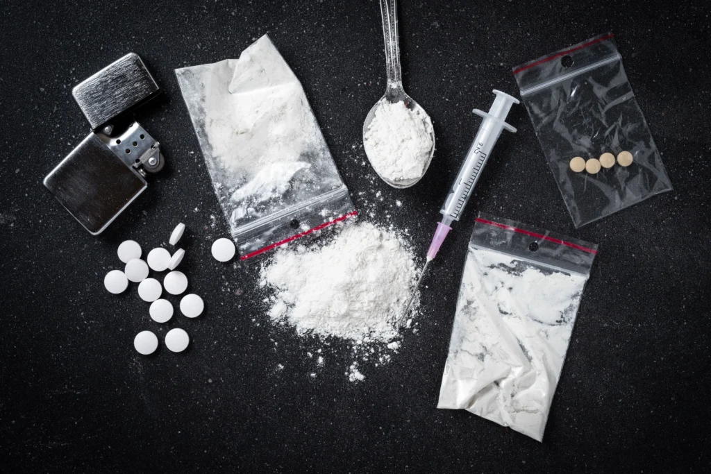 A pile of various drugs on a black table.