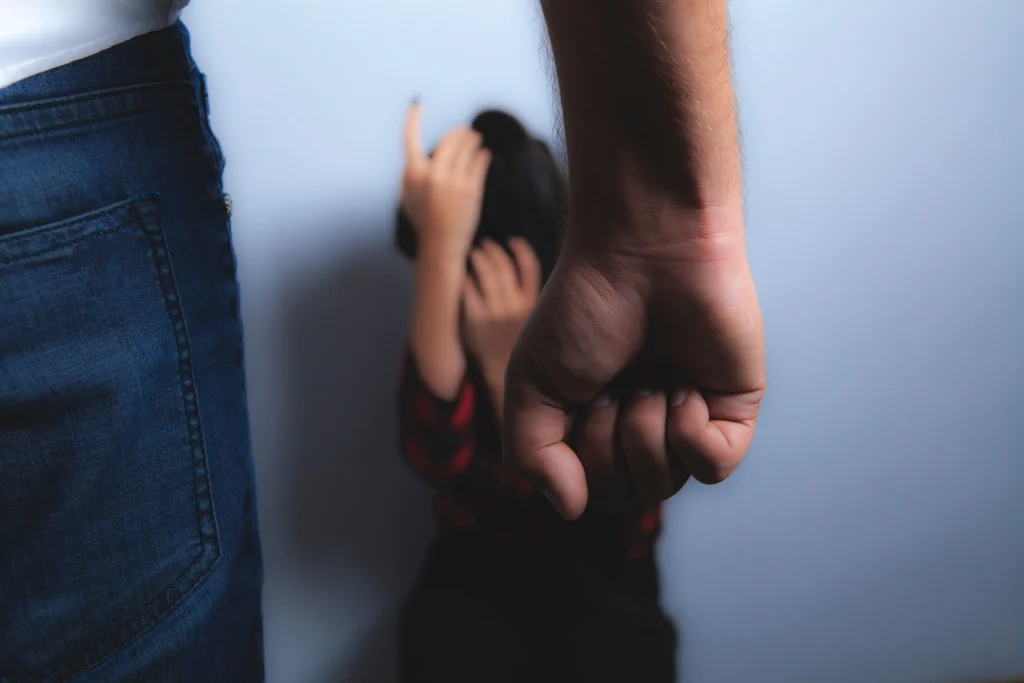 A man making a fist standing in front of a woman.